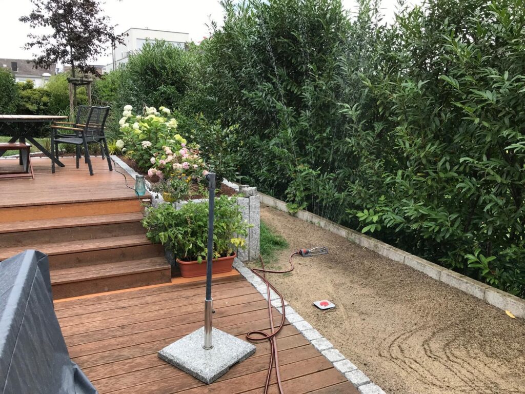 Holzterrasse mit angrenzendem Kiesweg – professionelle Gartenplanung vom Meisterbetrieb Thorsten Dallmann im Bergischen Land